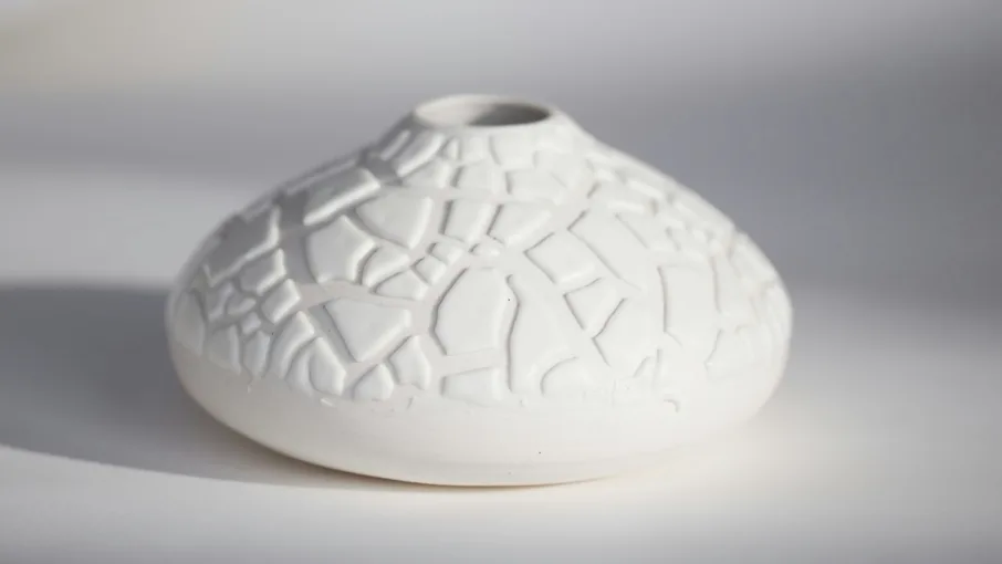 A white textured ceramic vase on a plain background