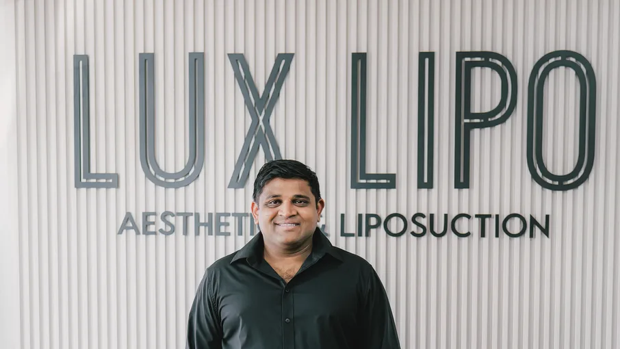 Dr. Vaibhav Desai, MD, at the Lux Lipo reception wall in Jonesboro