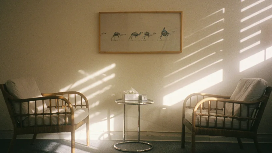Two chairs and a side table in a quiet, sunlit room